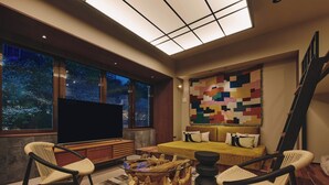 A modern living room with a large TV, comfortable seating, a unique coffee table, and a colorful quilt on the wall. - illi Toas Tokyo-Toranomon (Tokyo)