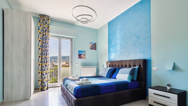 Ein Schlafzimmer mit einem großen Bett, einem Nachttisch und Blick ins Freie.
