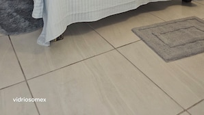 Um quarto com cama, mesa de cabeceira, um vaso e um tapete.