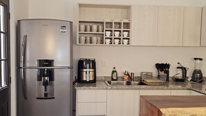 Uma cozinha moderna com frigorífico de aço inoxidável, máquina de café e pia.