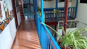 Un corridoio con ringhiera blu, pavimento piastrellato e una scala sullo sfondo.
