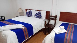 Una camera d'albergo con due letti, ciascuno con copriletto a righe blu e bianche, una testiera in legno e una sedia di legno.