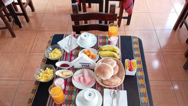 Una tavola imbandita con prodotti per la colazione, tra cui uova, pane e succo, su una tovaglia colorata.