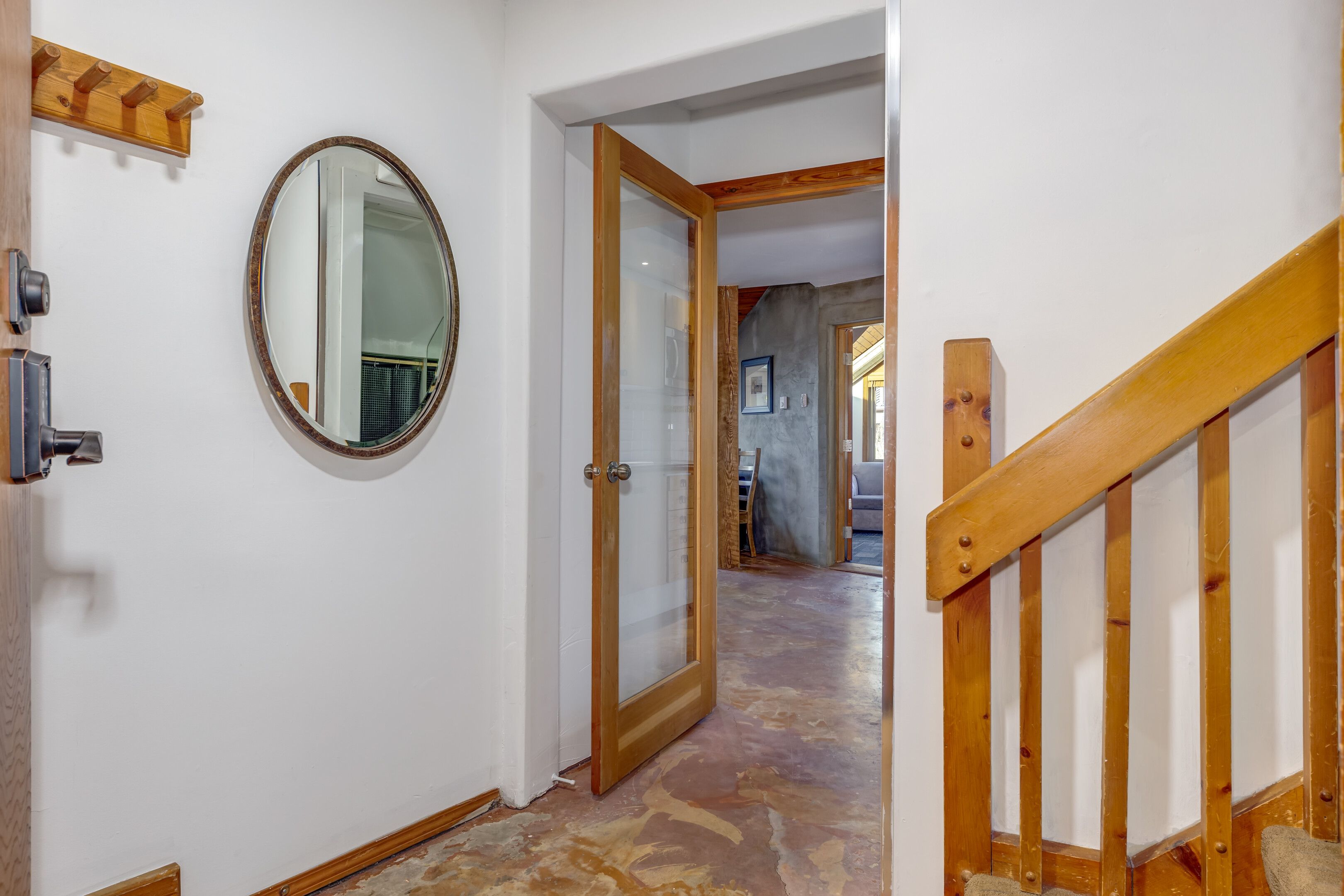 Ein Flur mit einer Holztür, einem Spiegel und einer Treppe mit einem Holzweg.