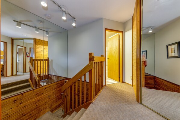A staircase with wooden railings and carpeted steps leading to a room with a wooden door and a framed picture on the wall. - Fitzsimmons D - 3BR in the Heart of Whistler Village, Private Sauna (Whistler)