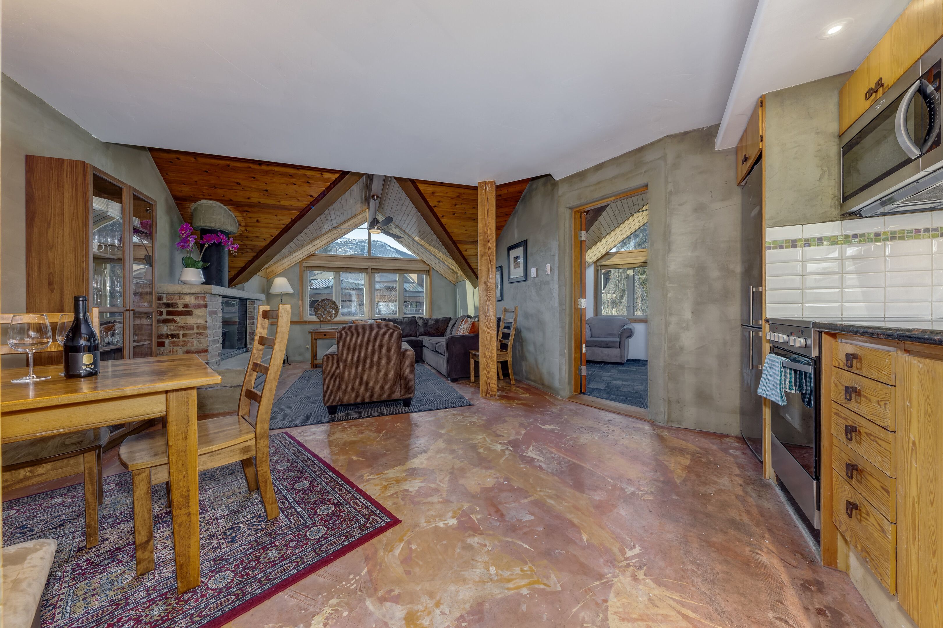 A spacious living area with a high ceiling, a dining table, and a kitchen area with modern appliances.