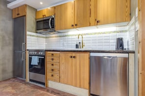 A kitchen with wooden cabinets, a stainless steel refrigerator, a microwave, a dishwasher, and a tiled backsplash. - Fitzsimmons D - 3BR in the Heart of Whistler Village, Private Sauna (Whistler)