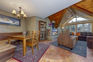 A spacious living area with a high ceiling, a dining table with chairs, a sofa, and a fireplace. - Fitzsimmons D - 3BR in the Heart of Whistler Village, Private Sauna (Whistler)