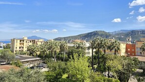 Un quartier résidentiel avec des immeubles, des palmiers et des montagnes en arrière-plan.