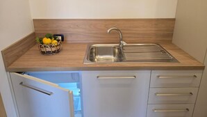 Une cuisine avec un évier en acier inoxydable, un plan de travail en bois et un panier de citrons.