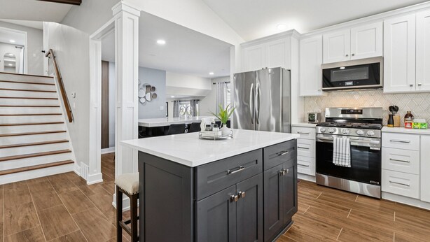 A modern kitchen with white cabinetry, a stainless steel refrigerator, a built-in oven, and a microwave. - Comfortable Luxurious 4BR Home w/ Game Room + Master Suite (Mount Prospect)