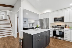 A modern kitchen with white cabinetry, a stainless steel refrigerator, a built-in oven, and a microwave. - Comfortable Luxurious 4BR Home w/ Game Room + Master Suite (Mount Prospect)