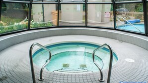 An indoor swimming pool with a tiled floor and metal pool ladders. - Slopeside Penthouse Apartment with Pool, Hot Tub and Sauna (Whistler)