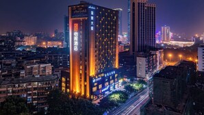 A high-rise hotel with illuminated signage, a prominent entrance, and a view of the surrounding cityscape at night. - ECHENG Liuzhou Wuxing Buxingjie (Liuzhou)