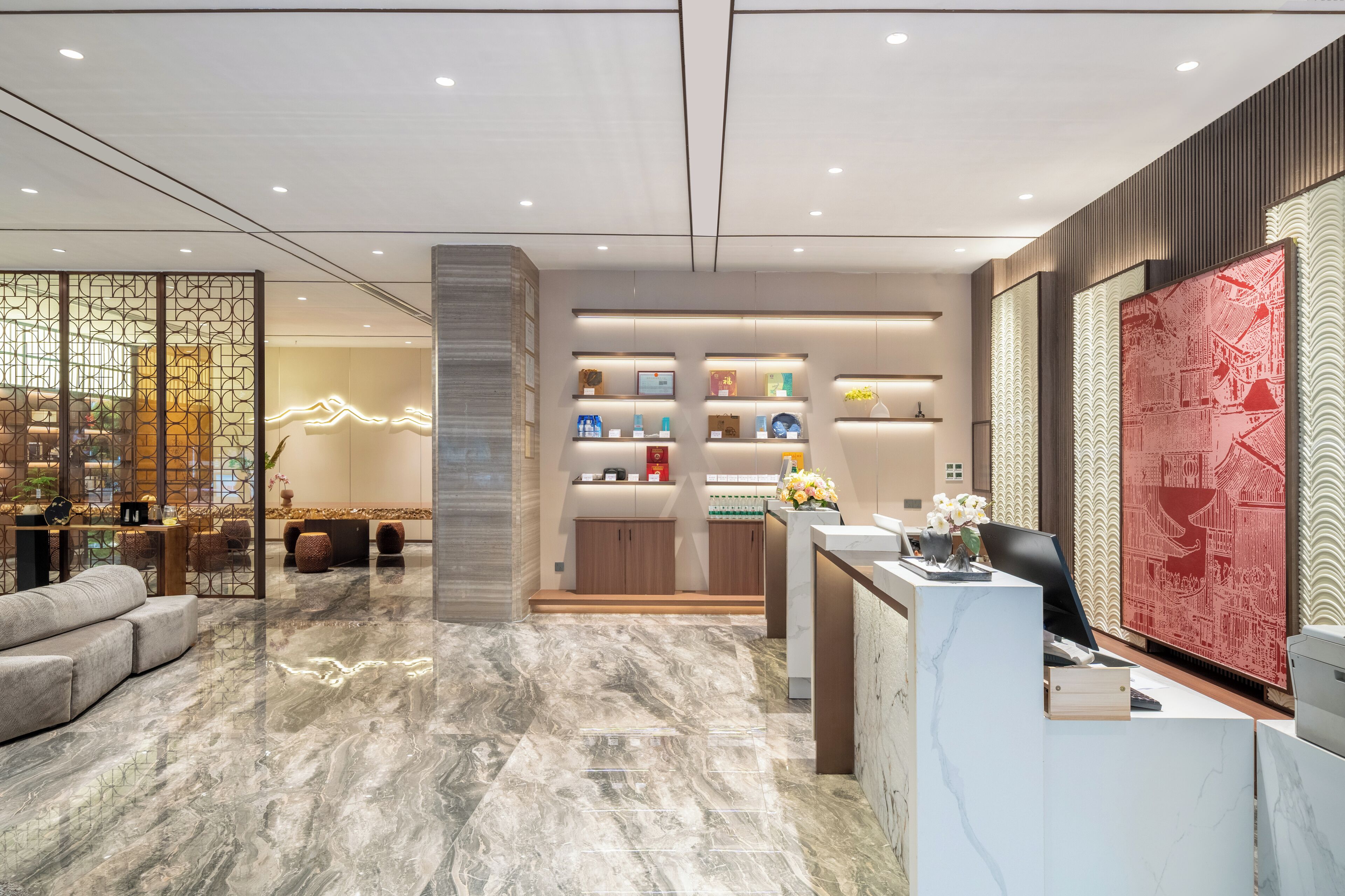 A modern hotel lobby with a reception desk, seating area, and decorative wall panels.