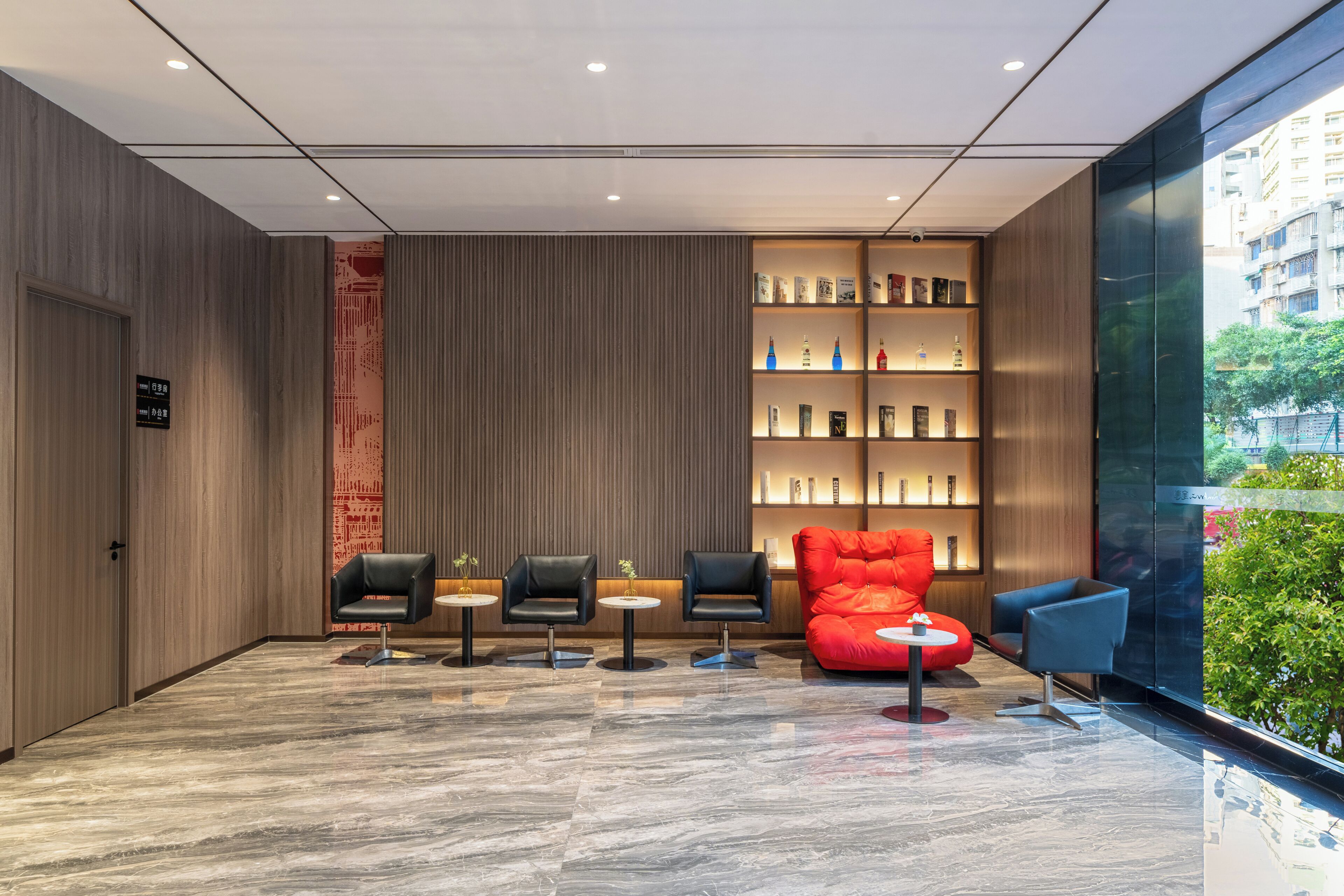 A modern lobby with a reception desk, seating area, and a bookshelf.