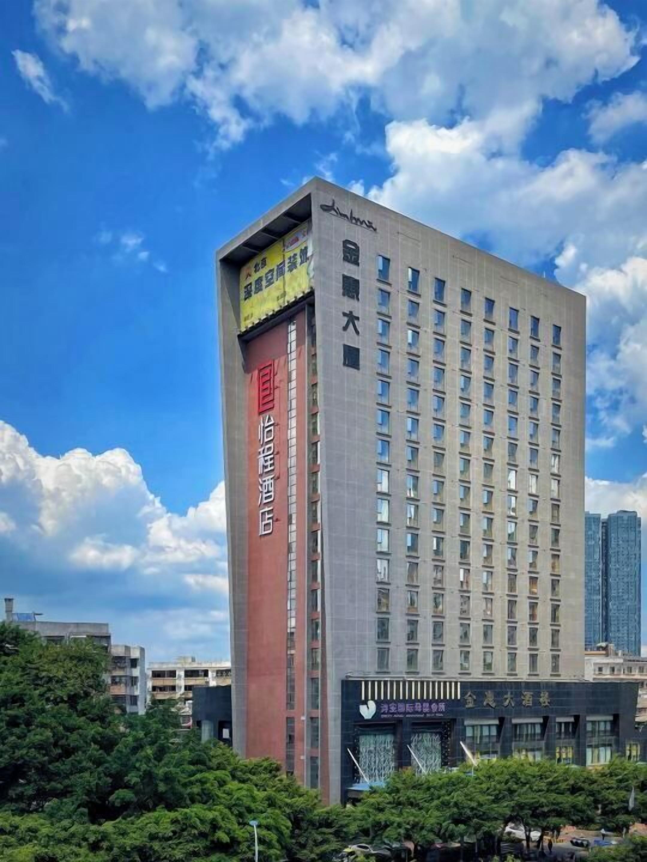 A tall hotel with multiple floors, a prominent red and grey facade, and a clear sky in the background.