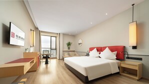 A modern hotel room with a large bed, a desk, a chair, a small table, a TV, and a view of the city. - ECHENG Liuzhou Wuxing Buxingjie (Liuzhou)