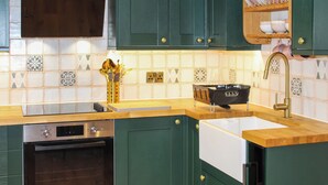 Una cucina con pensili verdi, forno a incasso, lavello e scolapiatti.