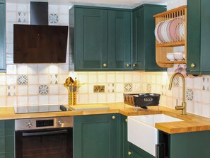 A kitchen with green cabinets, a built-in oven, a sink, and a dish rack. - The Cottage - UK50652 (Falmouth)