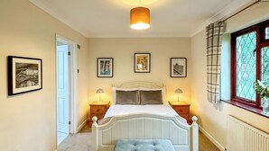 A bedroom with a bed, bedside tables, a bench, and framed pictures on the wall. - 1 bedroom accommodation in Tenby (Tenby)