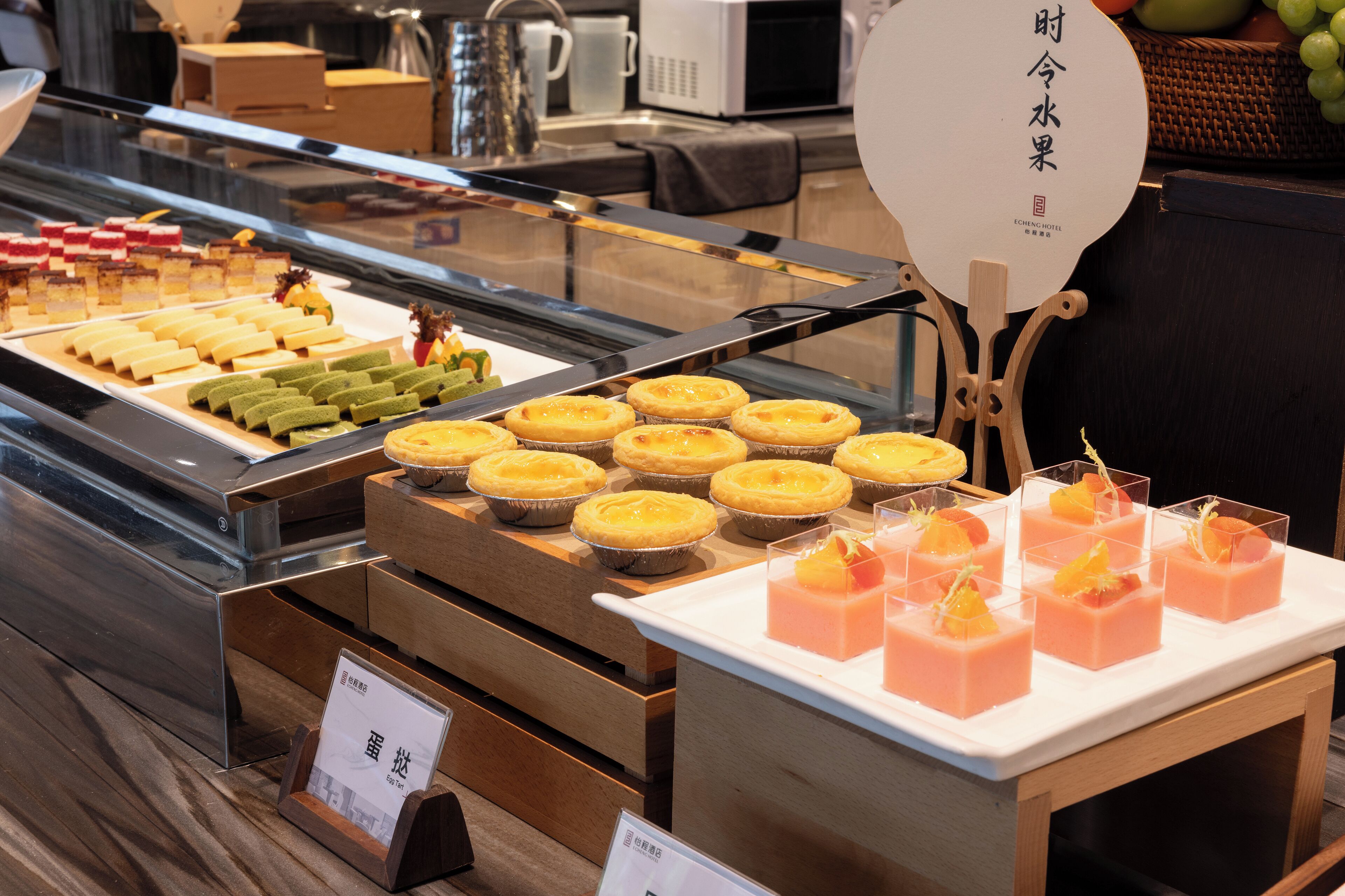 A display case with various desserts, including tarts and pastries, in a bakery or cafe setting.