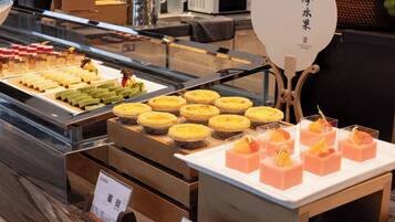 A display case with various desserts, including tarts and pastries, in a bakery or cafe setting.