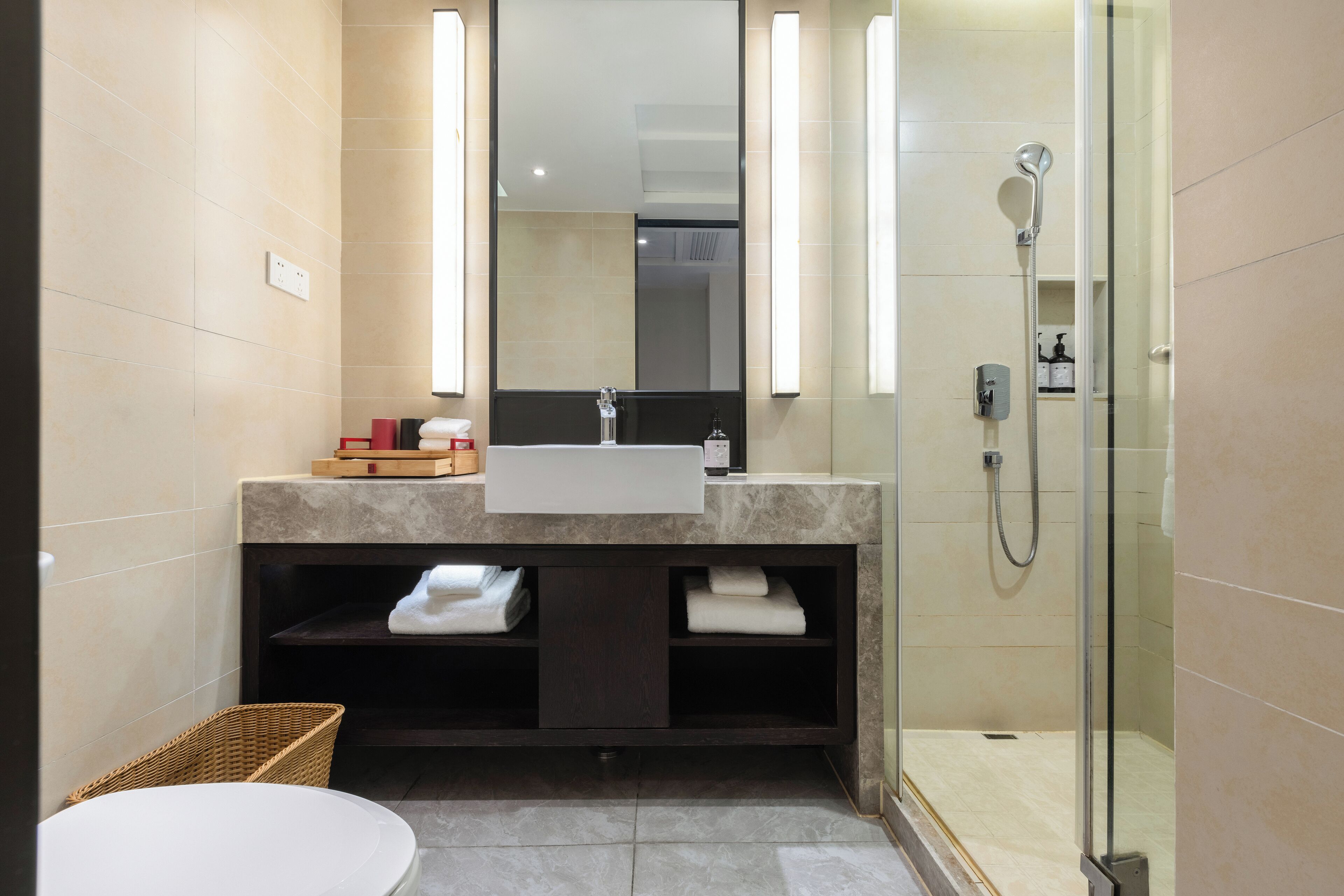 A modern bathroom with a white sink, a large mirror, and a glass-enclosed shower.