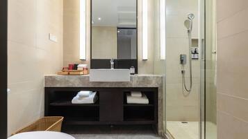 A modern bathroom with a white sink, a large mirror, and a glass-enclosed shower.