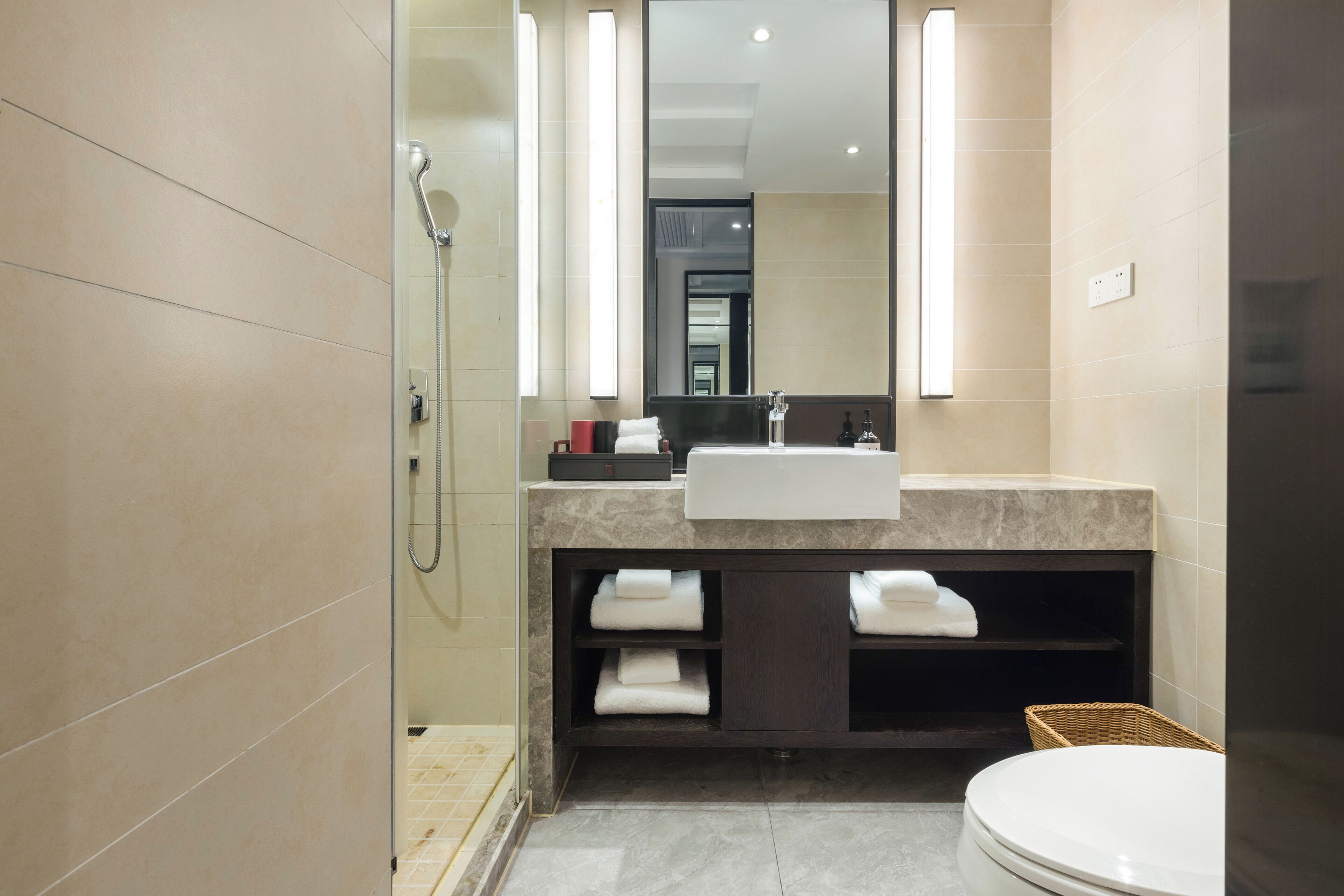 A modern bathroom with a glass shower enclosure, a sink with a mirror above, and a toilet.