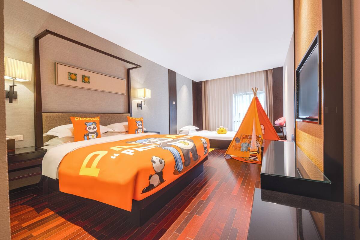 Una habitación de hotel con una cama grande, una mesita de noche, un televisor y una ventana con cortinas.