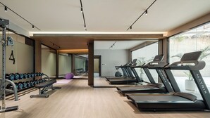 Un gimnasio moderno con cintas de correr, mancuernas y un espejo grande.
