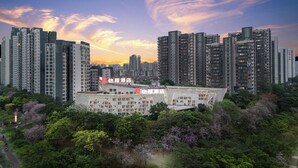 Un hotel moderno de gran altura, rodeado de abundante vegetación y árboles.
