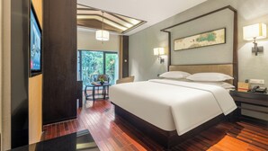 Habitación de hotel con una cama grande, un escritorio con lámpara, televisión y vistas al exterior.