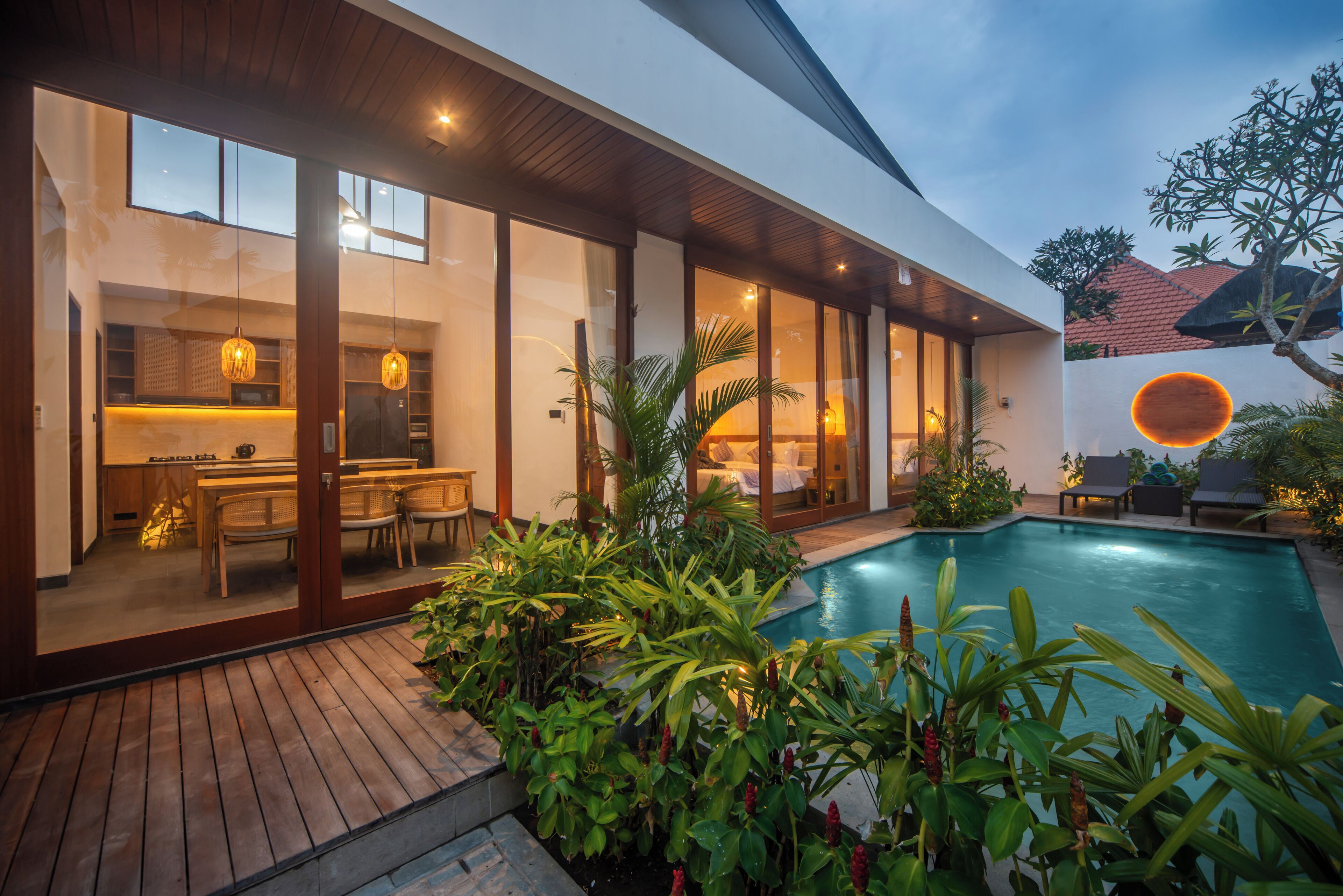 A modern house with a swimming pool, large windows, and a wooden deck.
