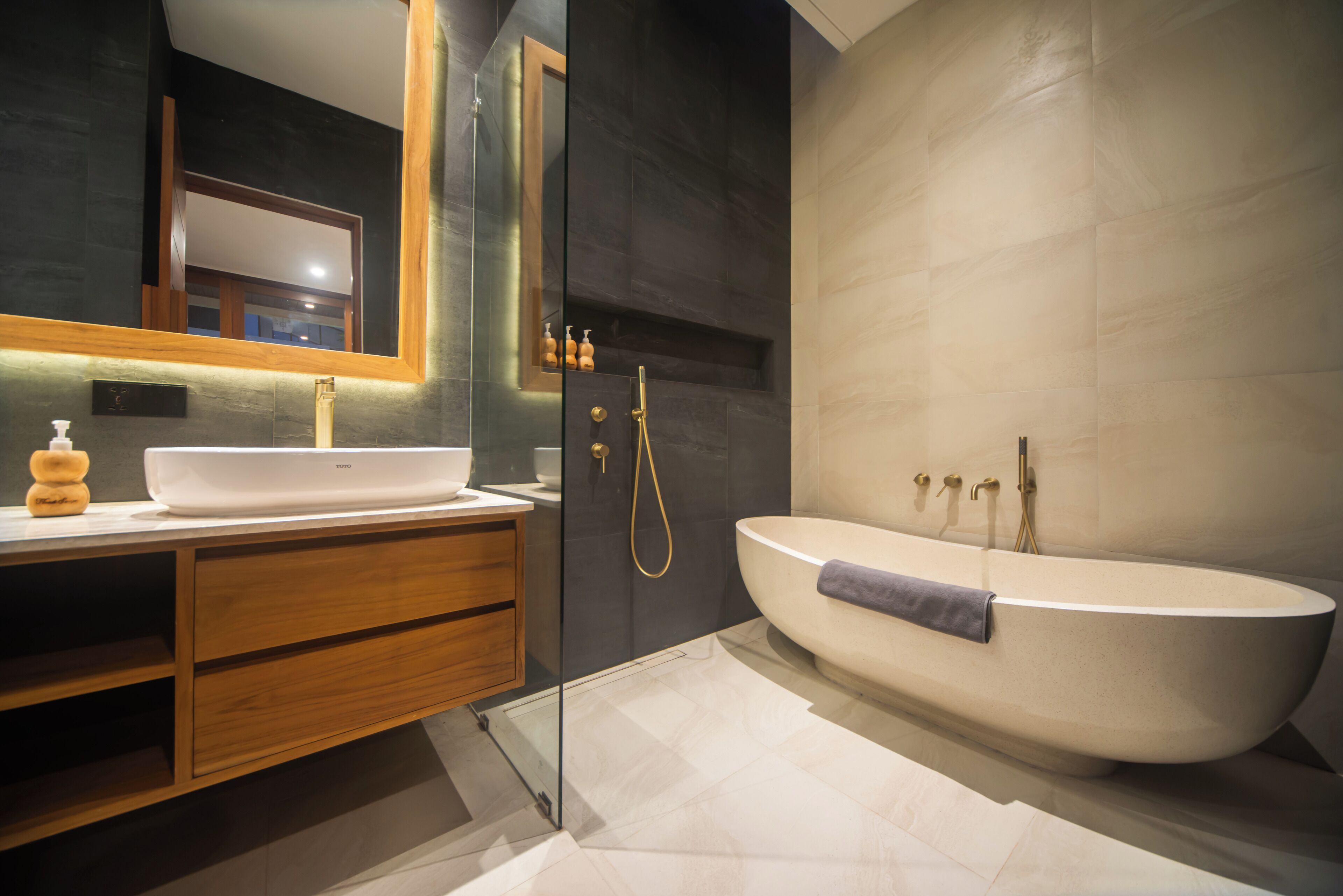 A modern bathroom with a freestanding bathtub, a large mirror, and a wooden vanity.
