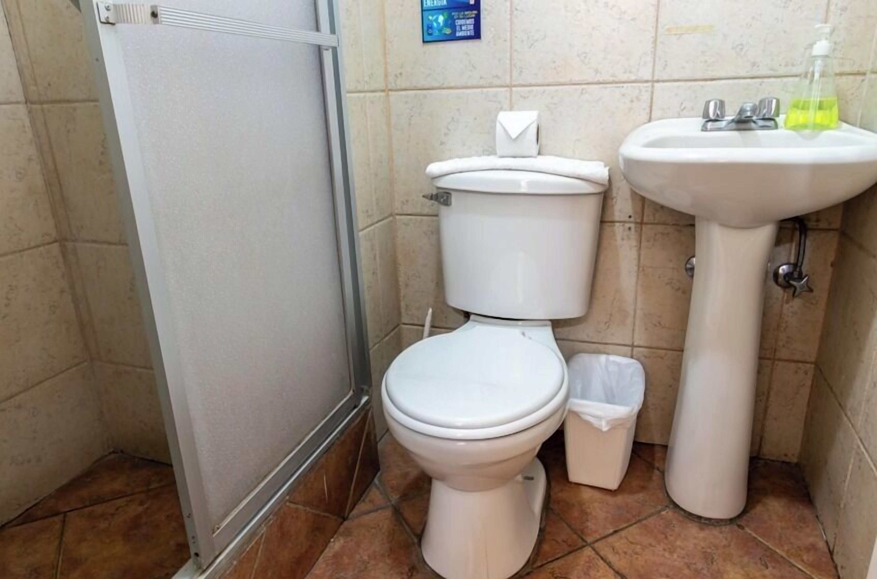 Une petite salle de bain avec des toilettes, un lavabo et une poubelle.