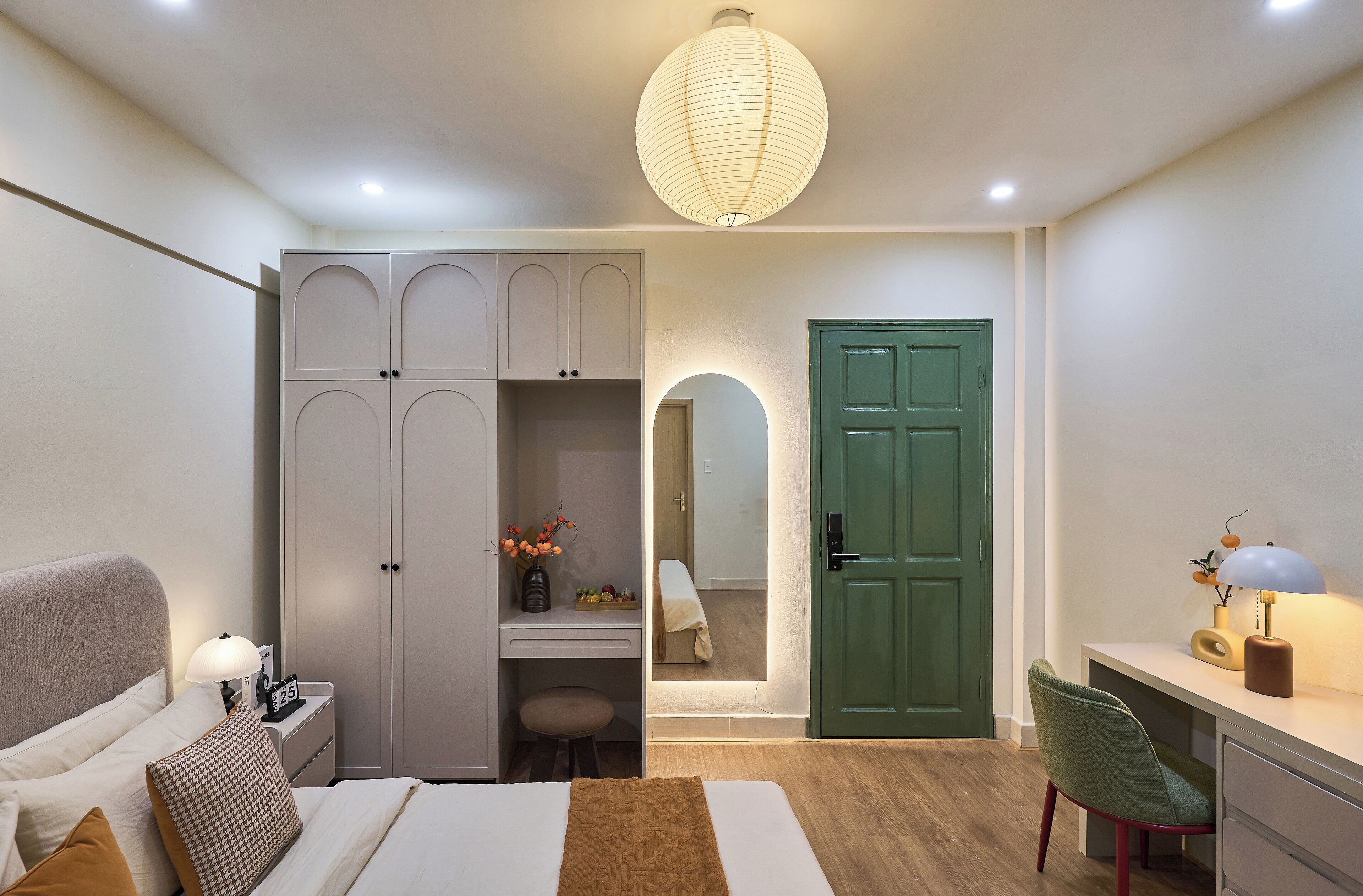Un dormitorio con cama, mesita de noche, armario, escritorio, silla y una puerta verde.