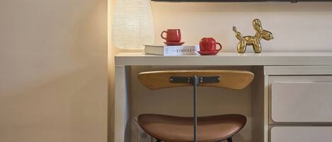 A desk with a lamp, a book titled 'The Kinfolk Home', a red cup, a red saucer, and a gold balsa wood sculpture.