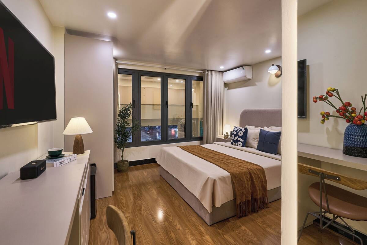 A hotel room with a bed, desk, chair, and a window with a view.