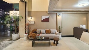 A hotel lobby with a reception desk, a sofa, a coffee table, and a potted plant. - Secret Garden Phan Xich Long (Ho Chi Minh City)