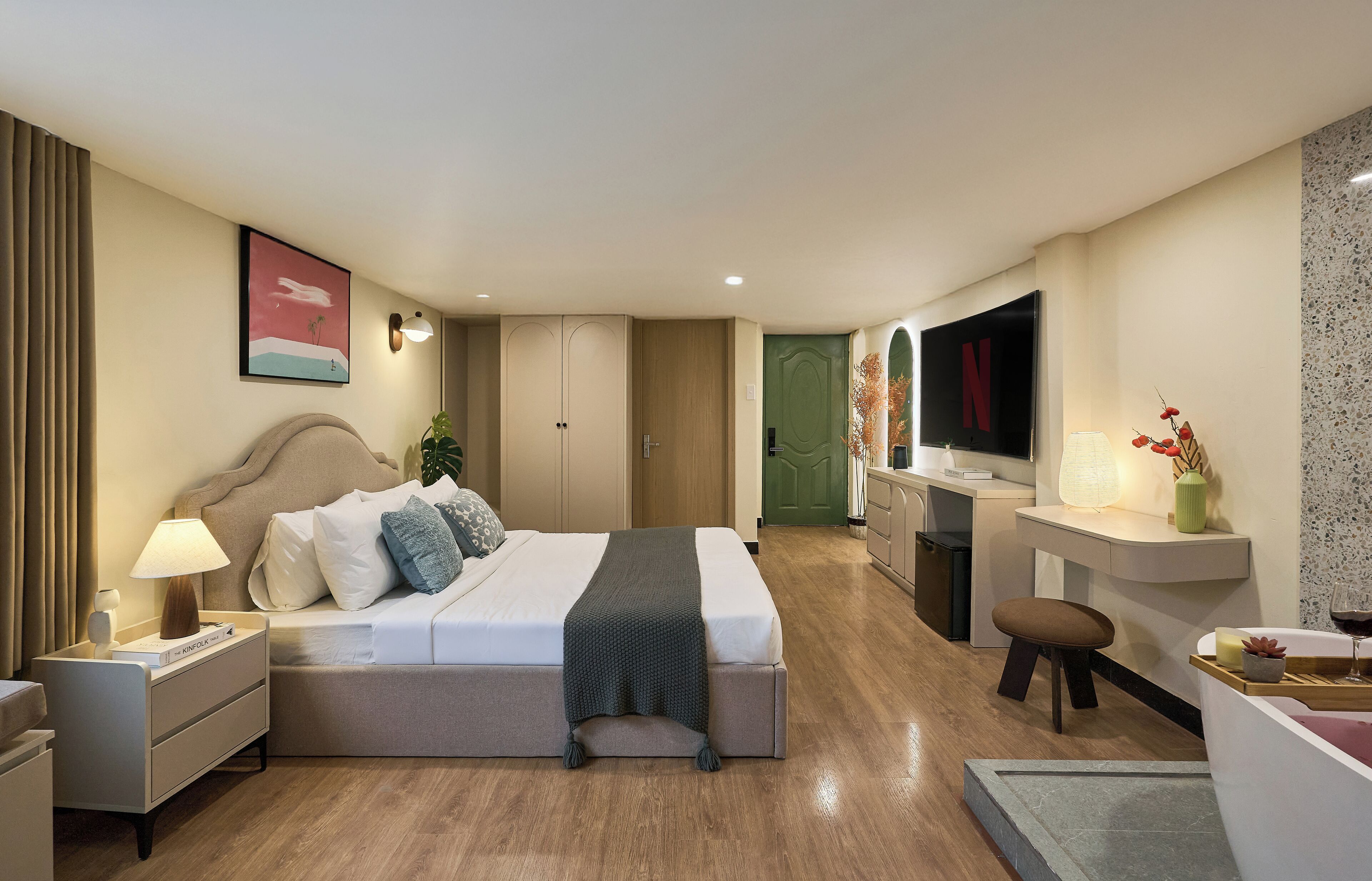 A modern hotel room with a large bed, bedside table, lamp, and a TV on a stand.