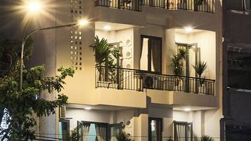 Un hotel de varios pisos con balcones, plantas en macetas y un letrero que dice 'Secret Garden Hotel'.