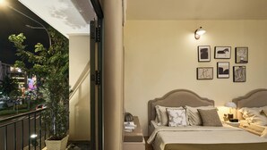 A bedroom with a bed, bedside tables, a nightstand, a potted plant, and framed pictures on the wall. - Secret Garden Phan Xich Long (Ho Chi Minh City)