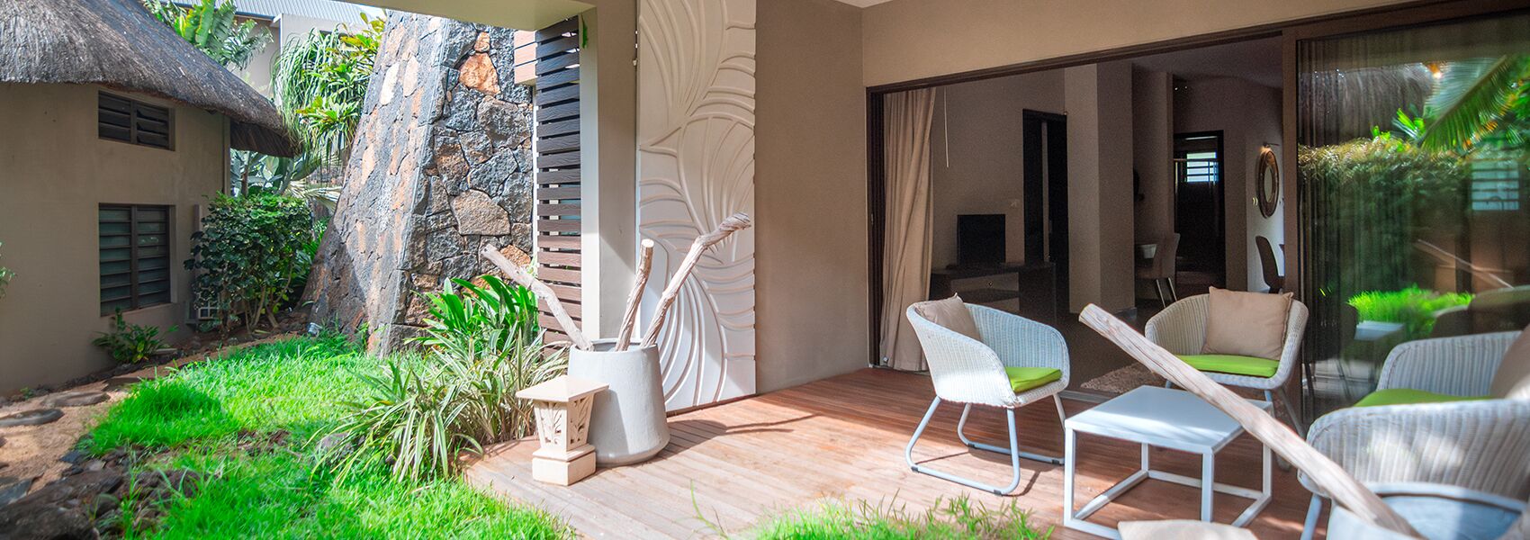 A patio with wicker chairs, a small table, and a decorative vase.
