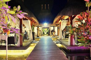 A pathway leading to a building with thatched roofs and indoor seating areas. - Residence Alizees Spa  (Grand-Baie)