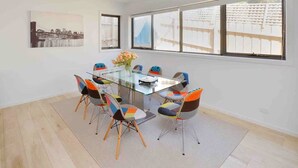 A modern dining area with a glass table, colorful chairs, and large windows offering a view of the cityscape.