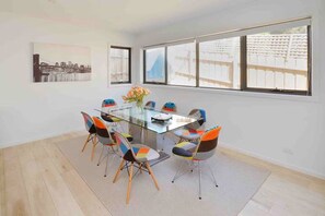 Un comedor moderno con una mesa de vidrio, sillas coloridas y ventanas amplias que ofrecen vistas de la ciudad.