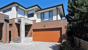 A modern two-story house with a garage and a stone facade.