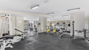Un gimnasio con diversas máquinas de ejercicio, una cinta de correr y un espejo grande.